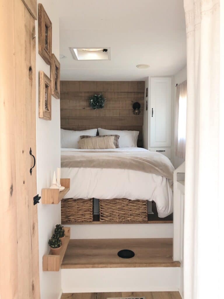 RV bedroom feature wall with cabinets removed and sconce lighting above the bed