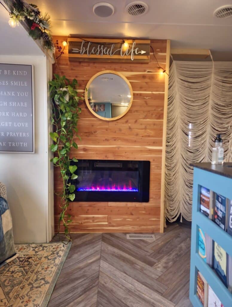 RV fireplace wall with cabinets removed and replaced with wood paneling and a mirror