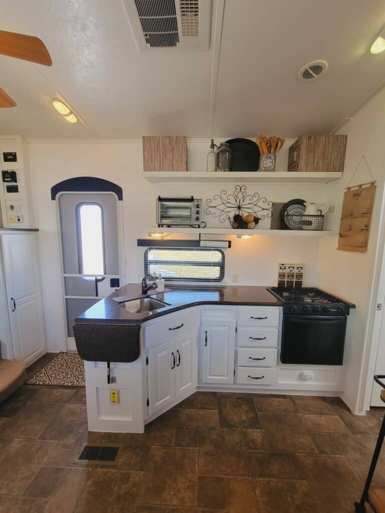 Bright white RV kitchen with upper cabinets removed around the windows